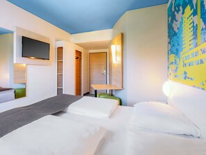 A hotel room with a bed, a desk, a chair, a TV mounted on the wall, and a closet. - B&B Hotel Stuttgart-City (Stuttgart)