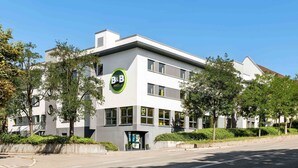 A modern B&B hotel with a white facade, large windows, and a green logo. - B&B Hotel Stuttgart-City (Stuttgart)
