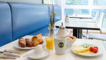 Desayuno con croissants, un huevo duro, zumo de naranja y un plato de queso y tomates.