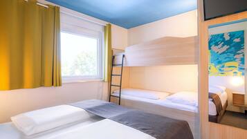 Habitación de hotel con dos camas, una ventana con cortinas, una litera, una escalera y un cuadro en la pared.