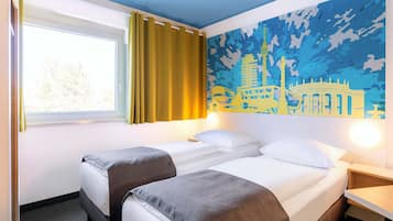 A hotel room with two beds, a window with curtains, a wall mural, and a bedside table.