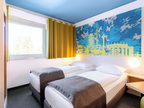 A hotel room with two beds, a window with curtains, a wall mural, and a bedside table. - B&B Hotel Stuttgart-City (Stuttgart)