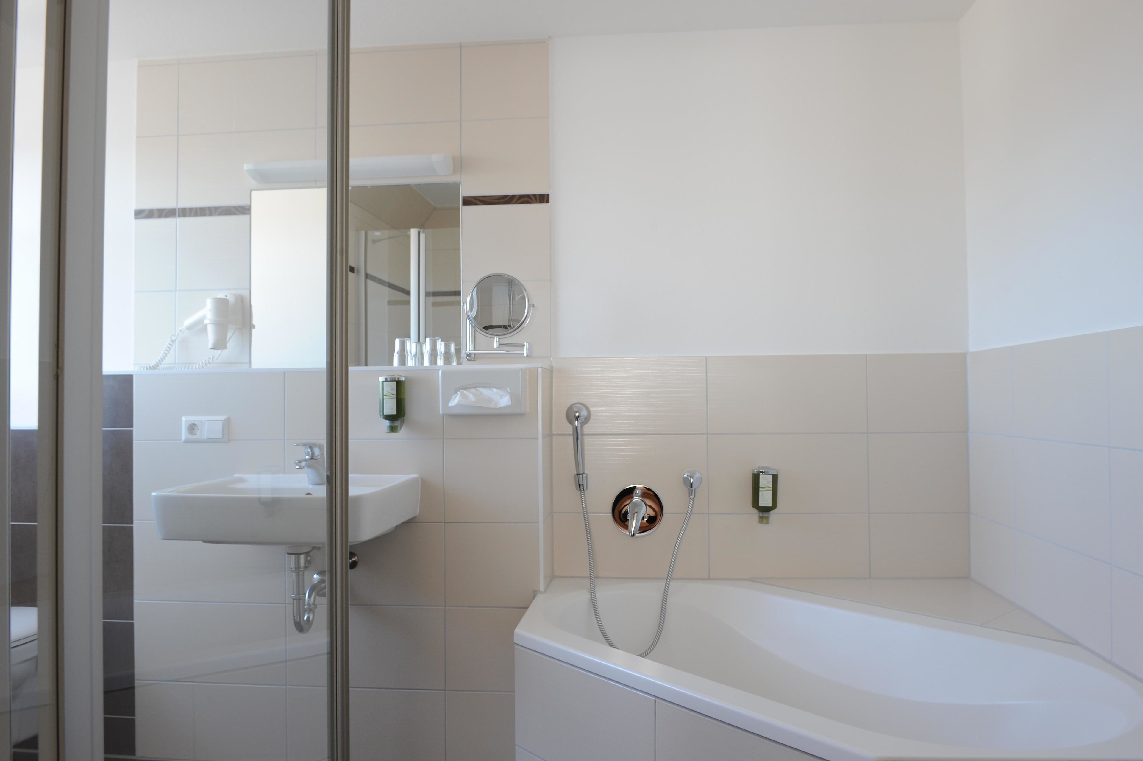 A modern bathroom with a sink, mirror, and bathtub.