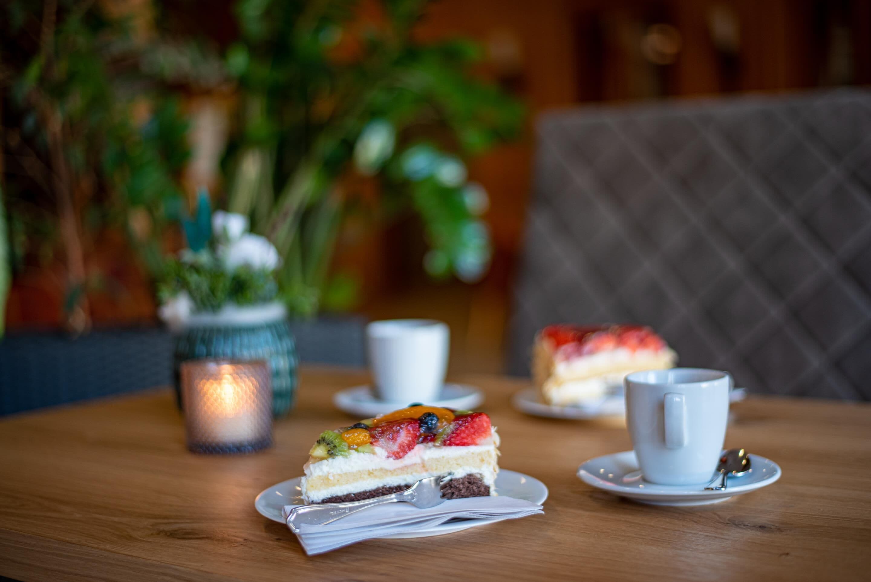 Un postre con fruta en un plato, una taza y una vela sobre una mesa.