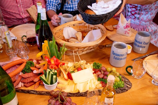 A table with a variety of food items including meats, cheeses, and vegetables, along with several bottles of wine and glasses.