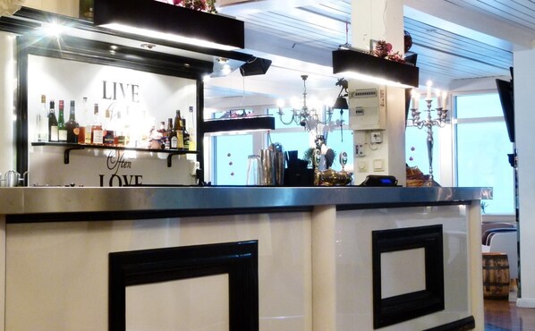 Uma área de bar com um letreiro 'LIVE', diversos tipos de garrafas e um candelabro.