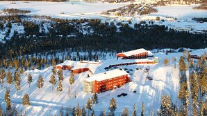 A snow-covered area with several buildings, including a red building with a white roof and a smaller red building with a white roof. - Hotell Silverhatten (Arjeplog)