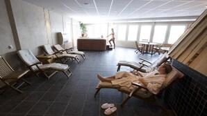 A spa area with multiple sun loungers, a reception desk, and a large window providing natural light. - Hotell Silverhatten (Arjeplog)
