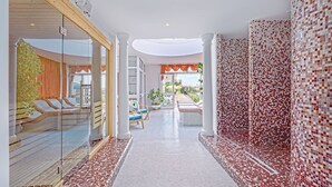 Un espacio de spa con pared de vidrio, techo de madera y paredes de azulejos.