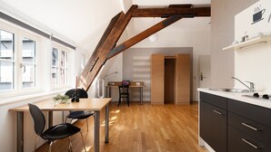 A modern kitchen with wooden flooring, a dining area with a table and chairs, and a built-in oven. - campuszwei Hotel & Boardinghouse (Ludwigsburg)