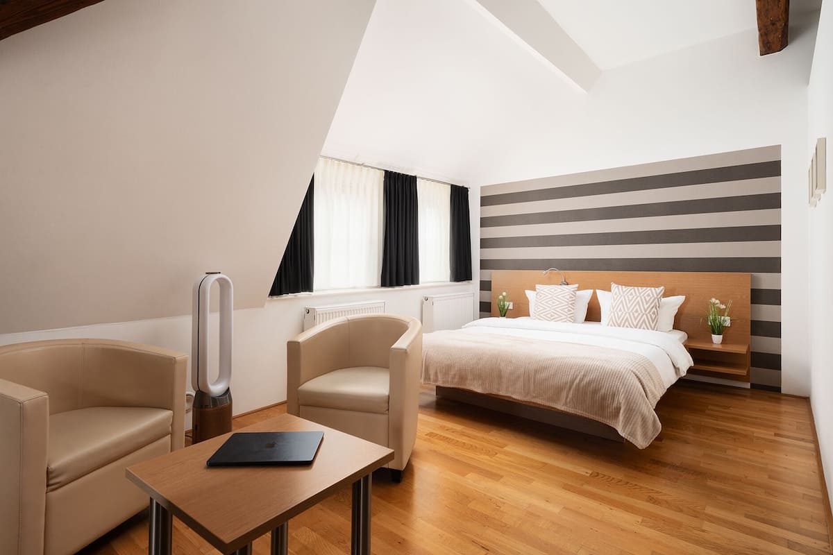 A modern bedroom with a bed, two chairs, a table, and a radiator.