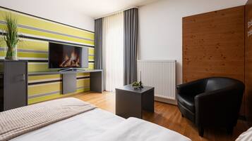 A modern hotel room with a bed, a TV, a desk, a chair, and a wooden accent wall.