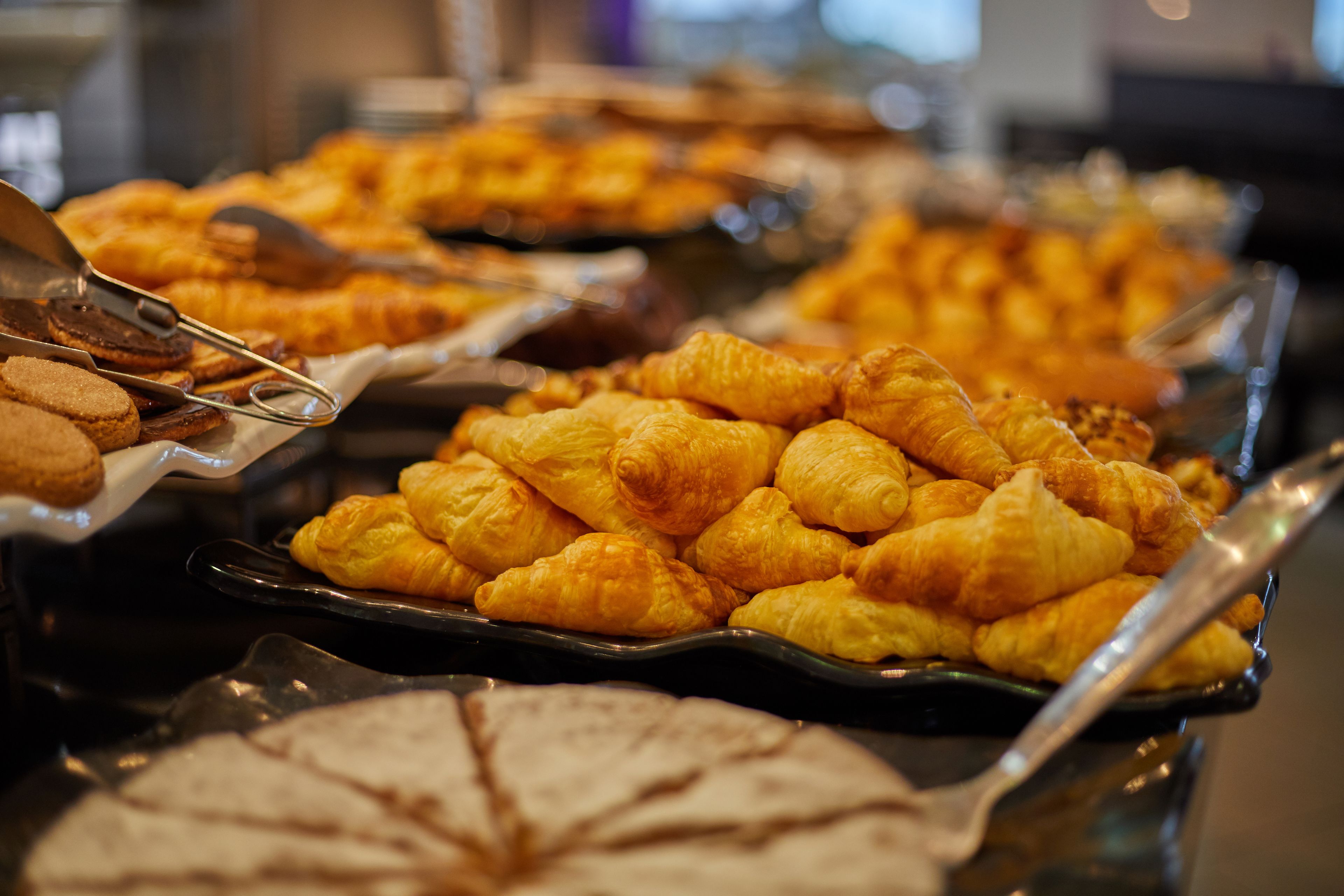 Un bufé con diversas opciones de panadería, incluyendo croissants y pasteles.