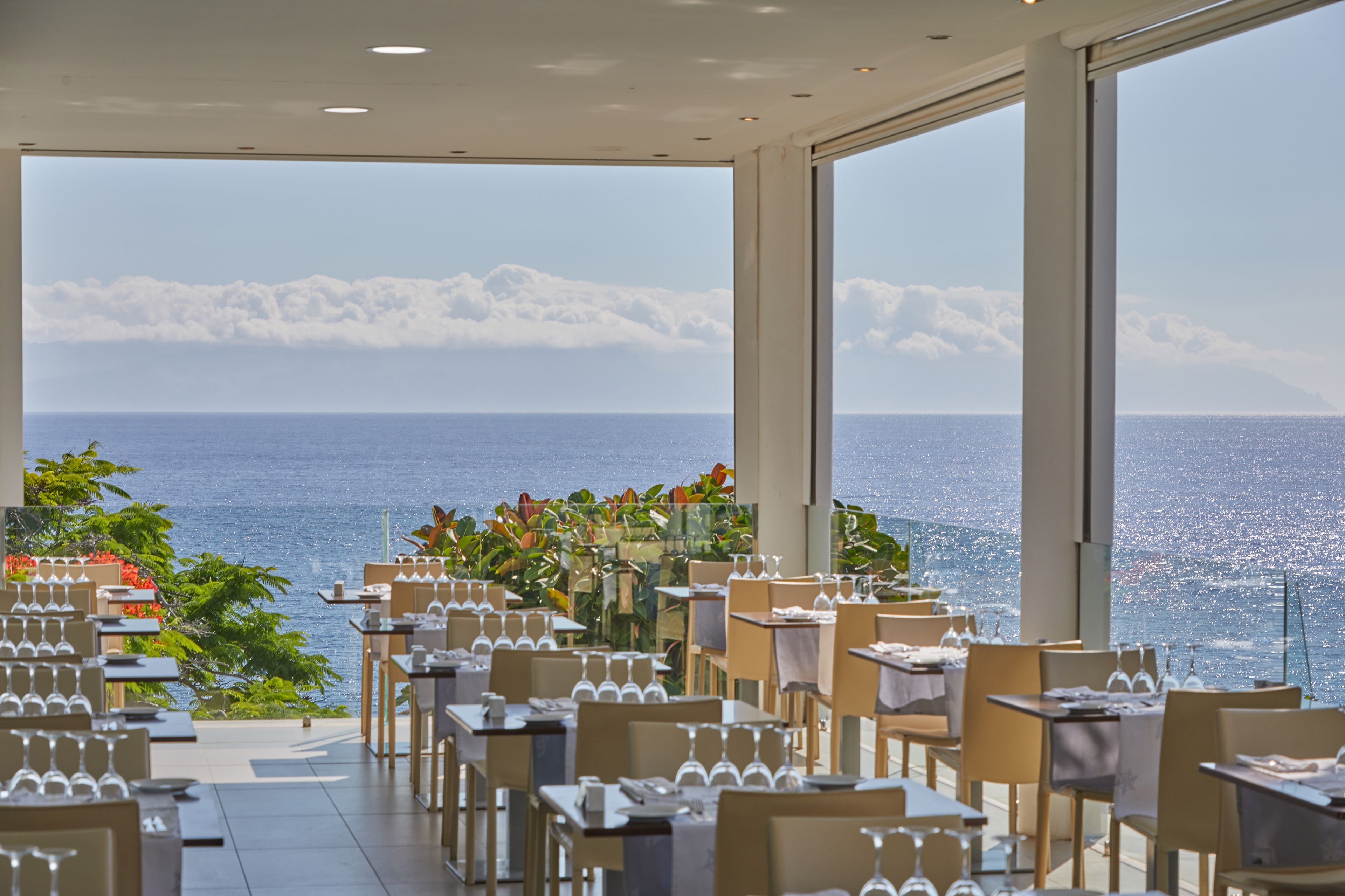 A restaurant with tables and chairs arranged for dining, overlooking a body of water.