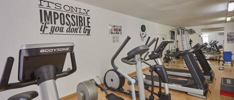 A gym with various exercise equipment, motivational wall art, and a wooden floor.