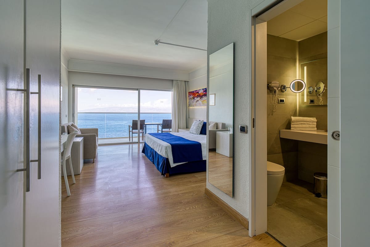 Ein modernes Hotelzimmer mit Balkon, einem Bett, einem Schreibtisch und einem Badezimmer.
