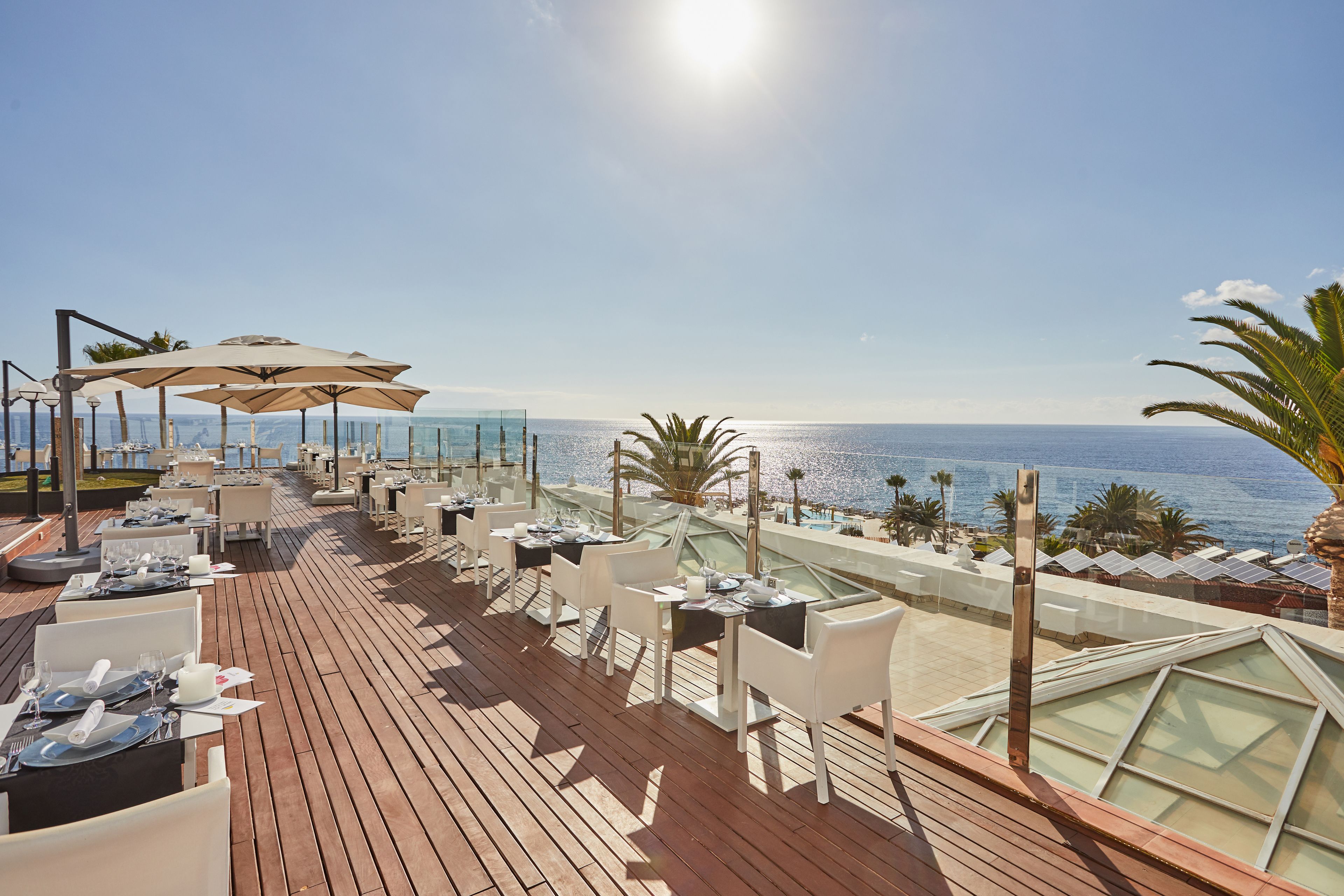Une terrasse sur le toit, avec des tables et des chaises, d’où l’on a une vue sur la mer.