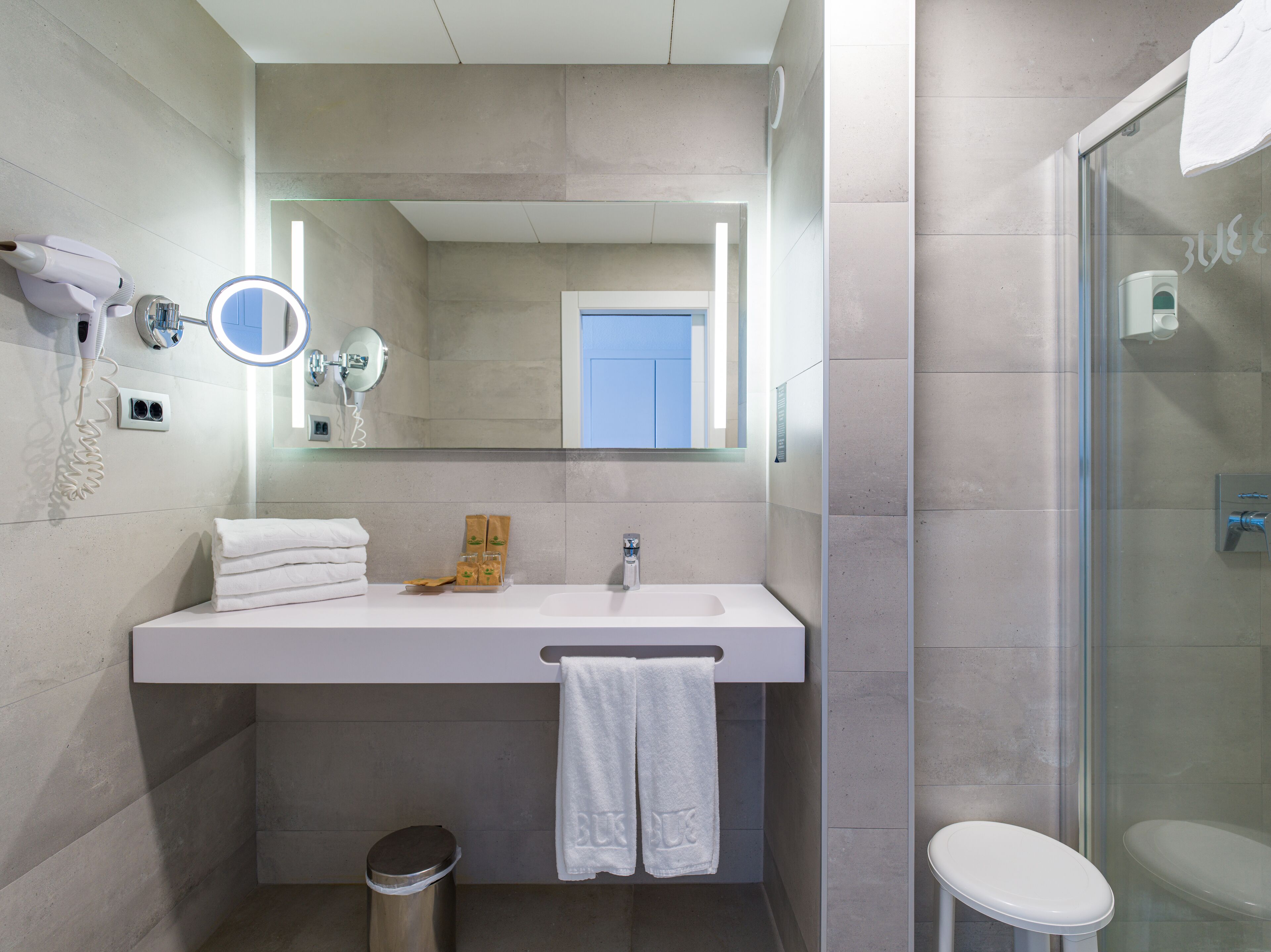 A modern bathroom with a large mirror, a sink, and a toilet.