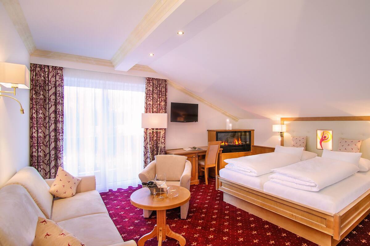 Ein Hotelzimmer mit einem Bett, zwei Sesseln, einem Schreibtisch, einem Fernseher und einem Kamin.