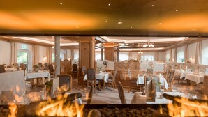 Un restaurant doté de nombreuses tables et chaises, d’un mur décoratif central et d’un foyer en évidence.