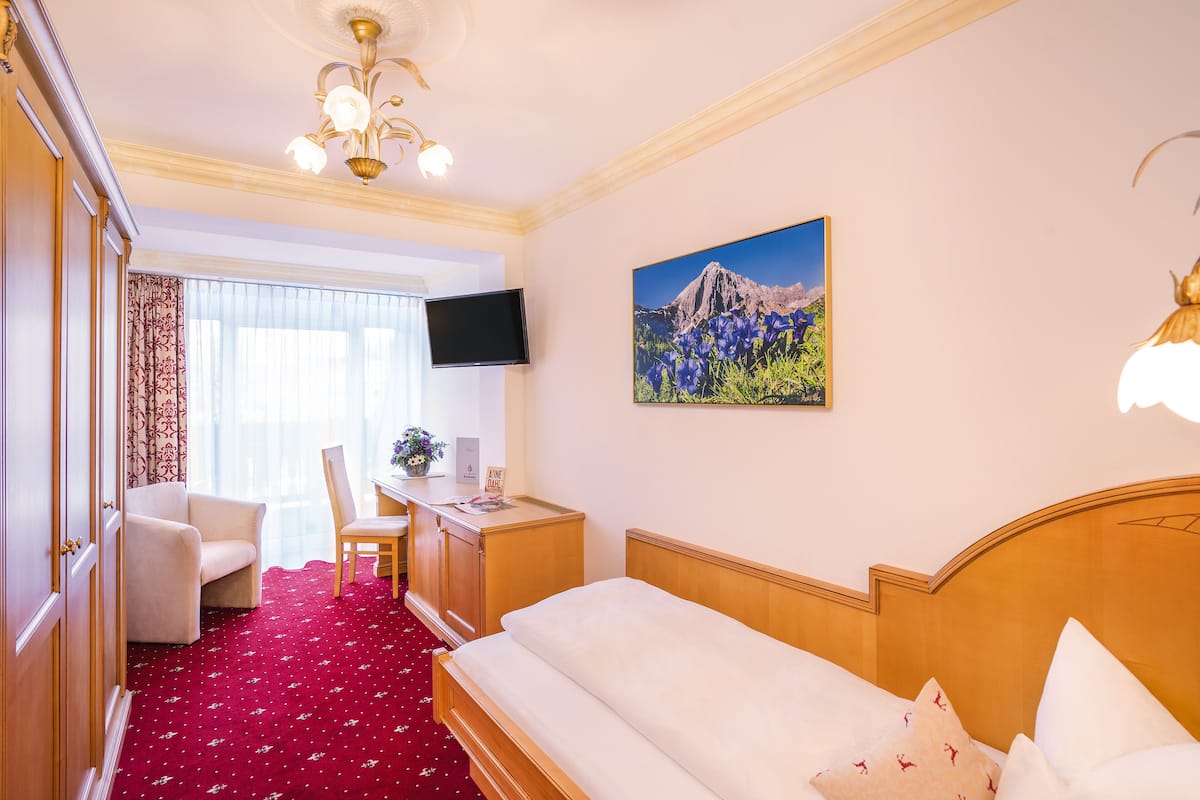 Ein Hotelzimmer mit Bett, Schreibtisch, Stuhl, Fernseher und einem Bild an der Wand.