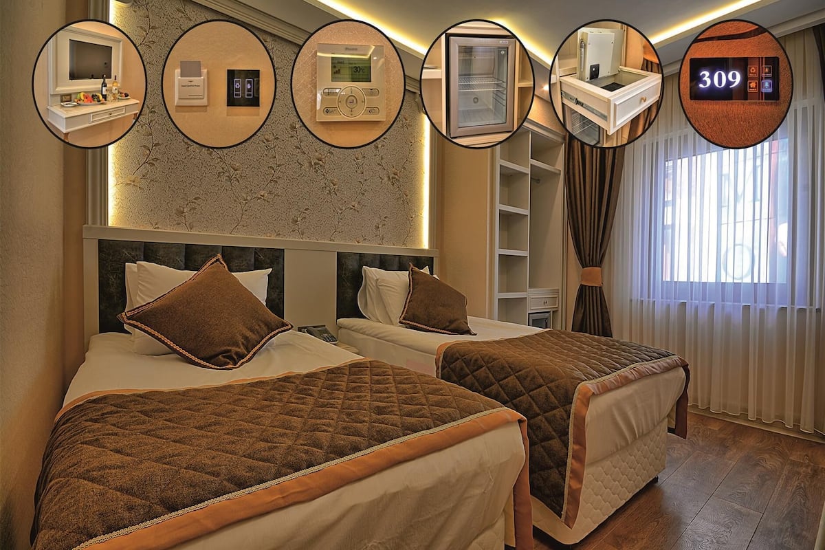 A hotel room with two beds, a minibar, a thermostat, a wardrobe, and a digital display showing the room number 309.