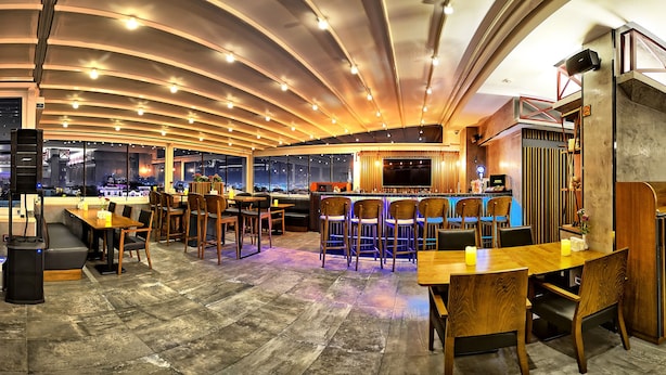 A modern restaurant with a bar area, wooden furniture, and large windows offering city views. - Samir Deluxe Hotel (Istanbul)