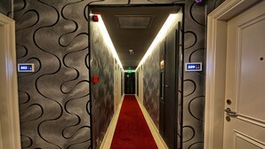 A hallway with a red carpet, numbered doors, and a patterned wall. - Samir Deluxe Hotel (Istanbul)