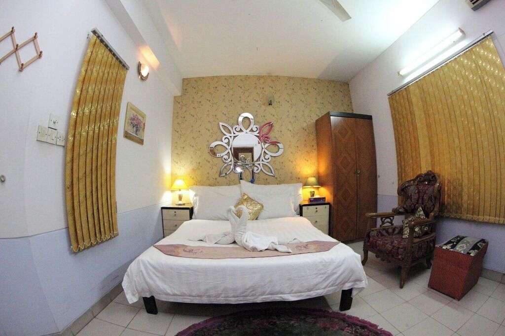 A hotel room with a bed, a decorative wall piece, a chair, and a small table.