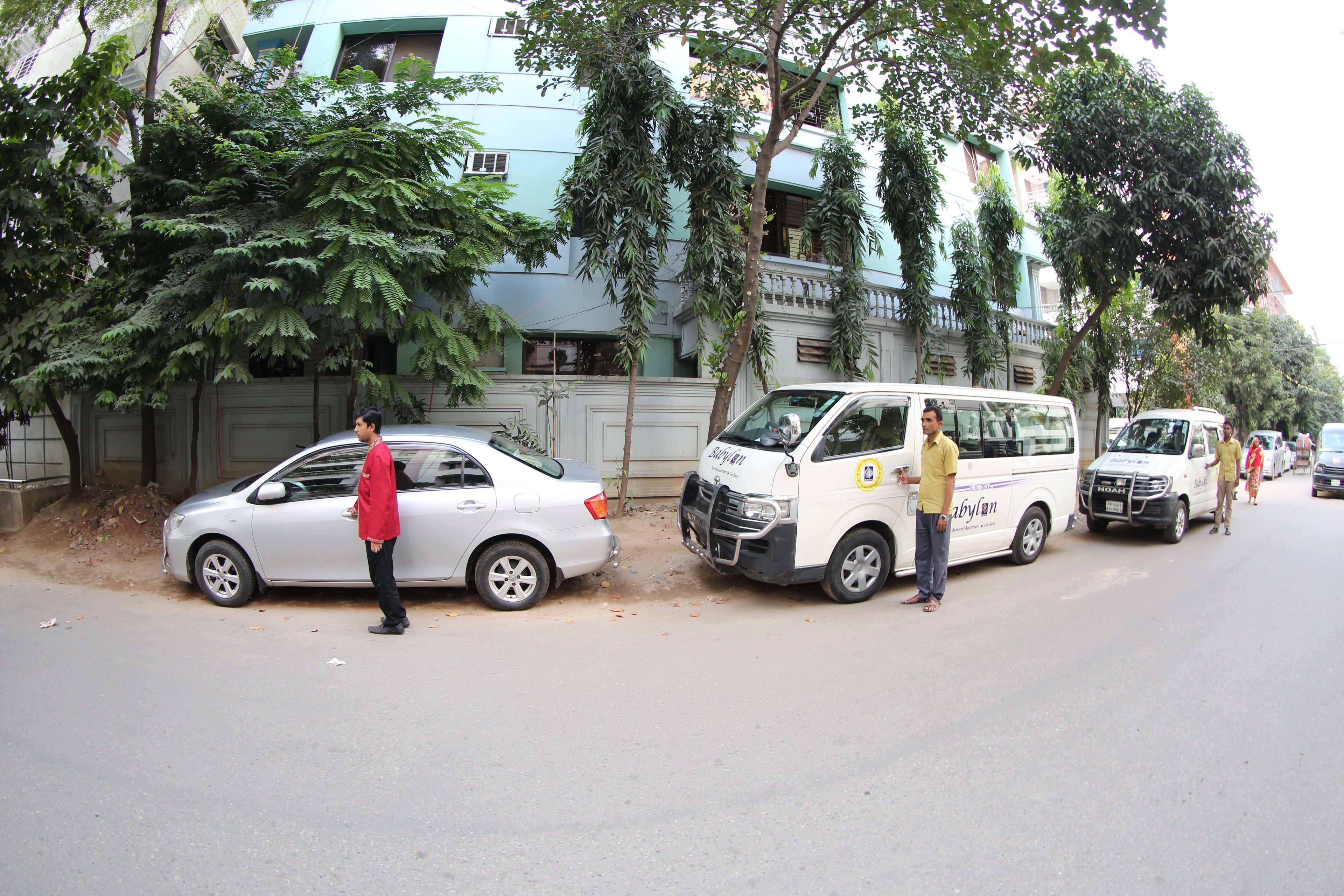 A street scene with parked vehicles and a person standing by a car.