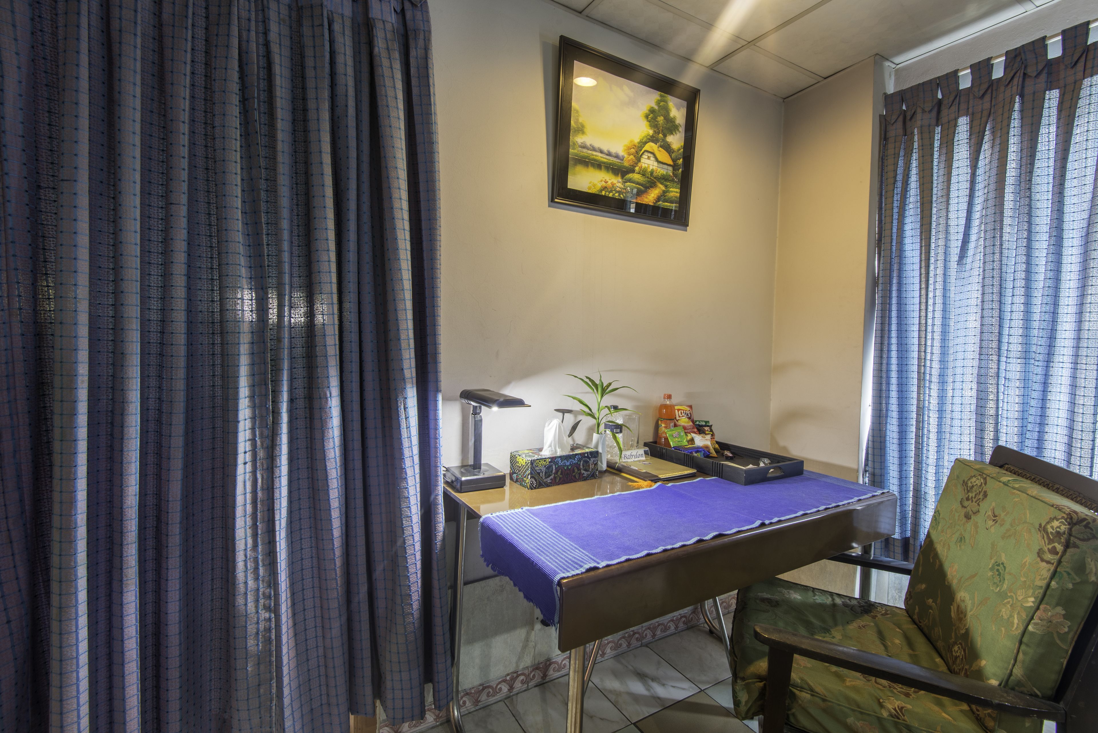 A room with a desk, chair, and a painting on the wall.