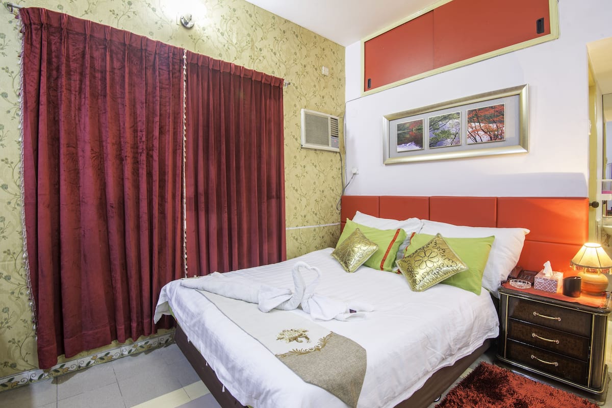 A hotel room with a bed, a nightstand, a lamp, and a framed picture on the wall.