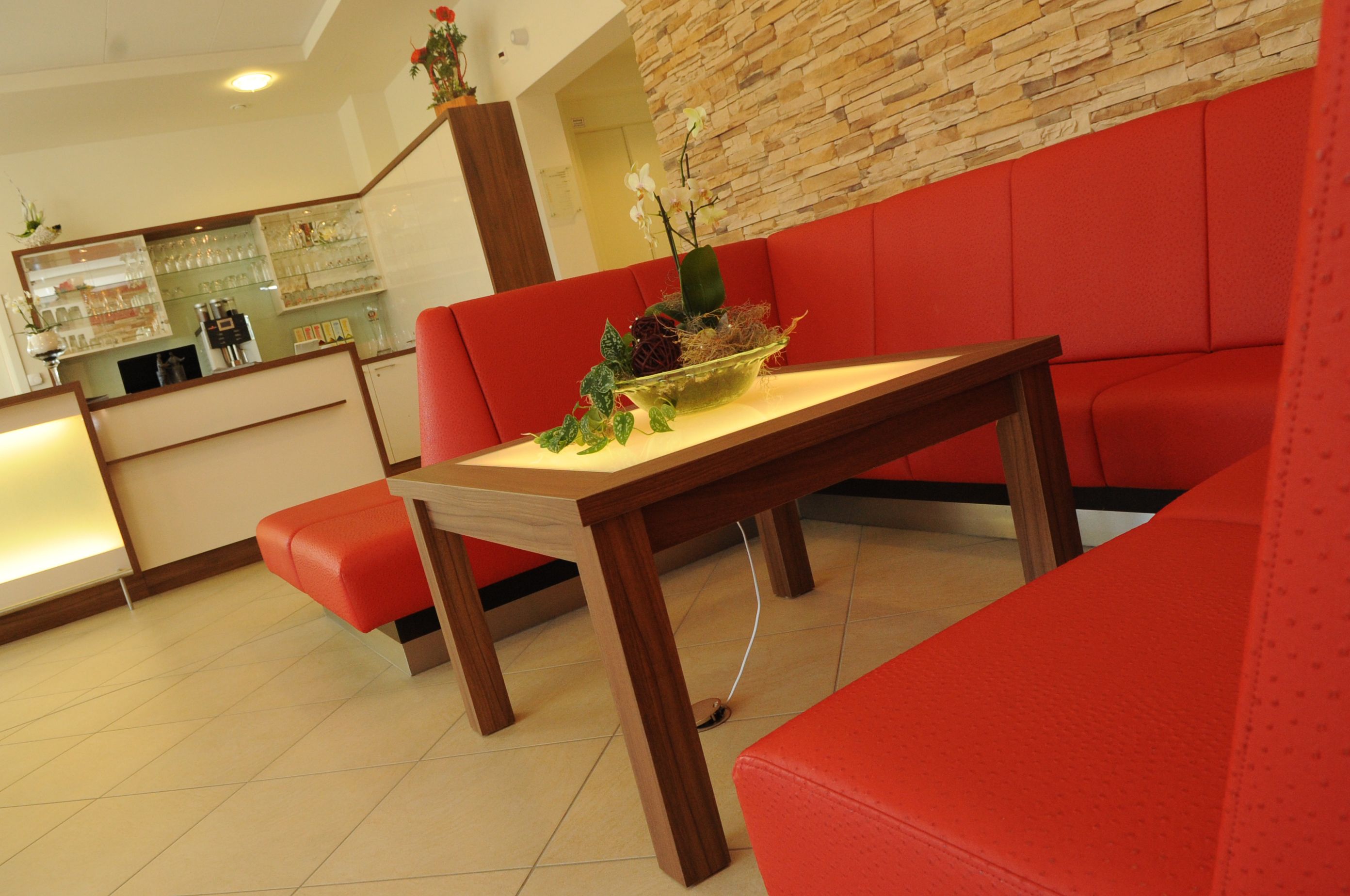Un interior moderno con una mesa de madera y asientos tapizados en rojo.