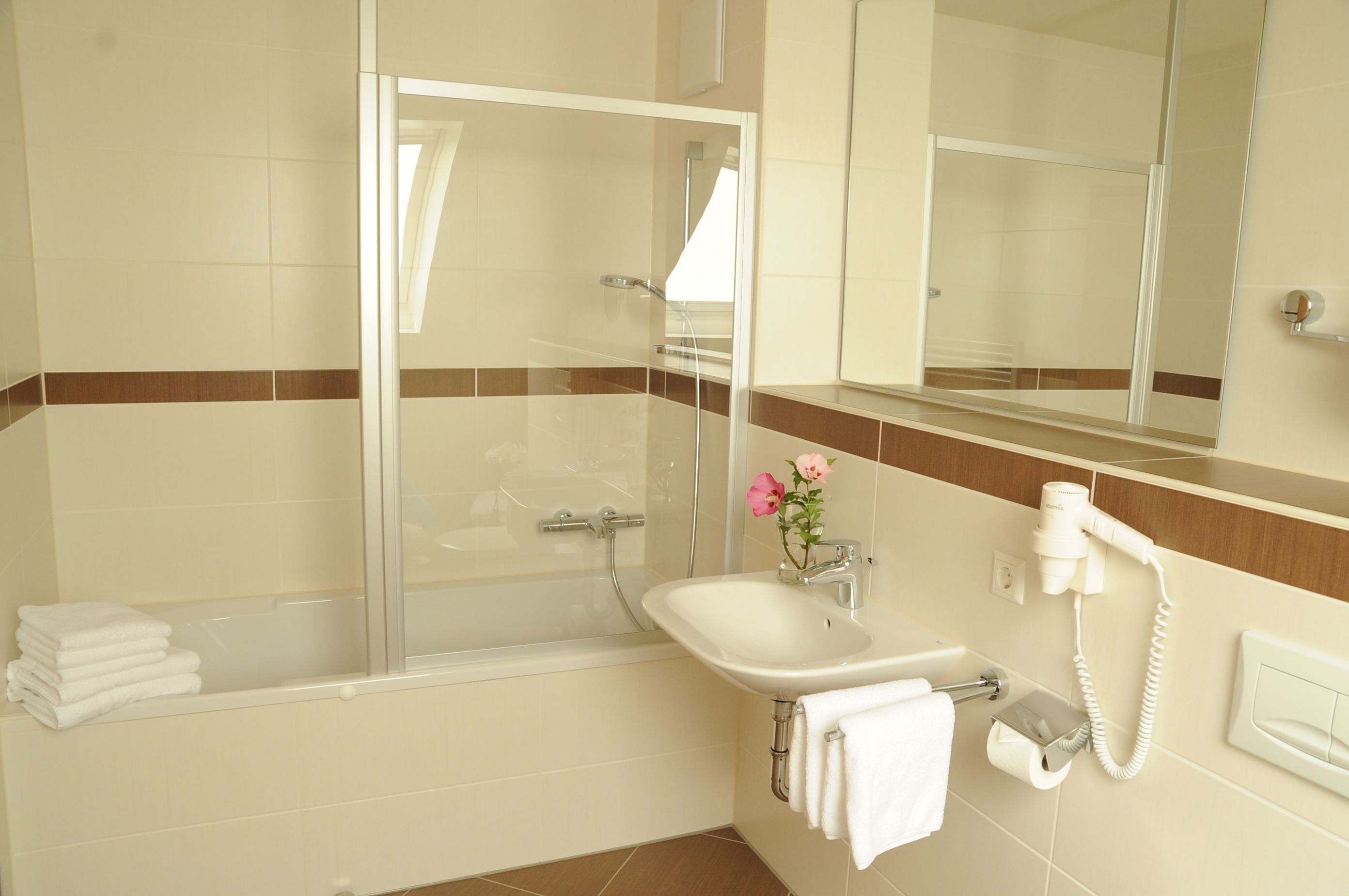 A bathroom with a bathtub, a sink, a mirror, and a hairdryer.