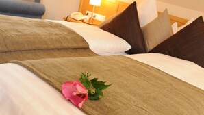 A hotel room with two beds, each with a brown bedspread and white pillows. A pink flower is placed on the bedspread of the bed on the left. - Beierleins Hotel & Catering GmbH (Callenberg)