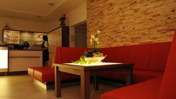 Un intérieur moderne avec un canapé rouge, une table en bois ornée d’un vase, et un coin bar à l’arrière-plan.