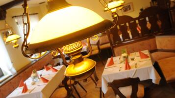 A dining area with tables set for service, hanging lamps, and wooden furniture.