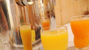 Um dispensador de suco com três copos de sumo de laranja.