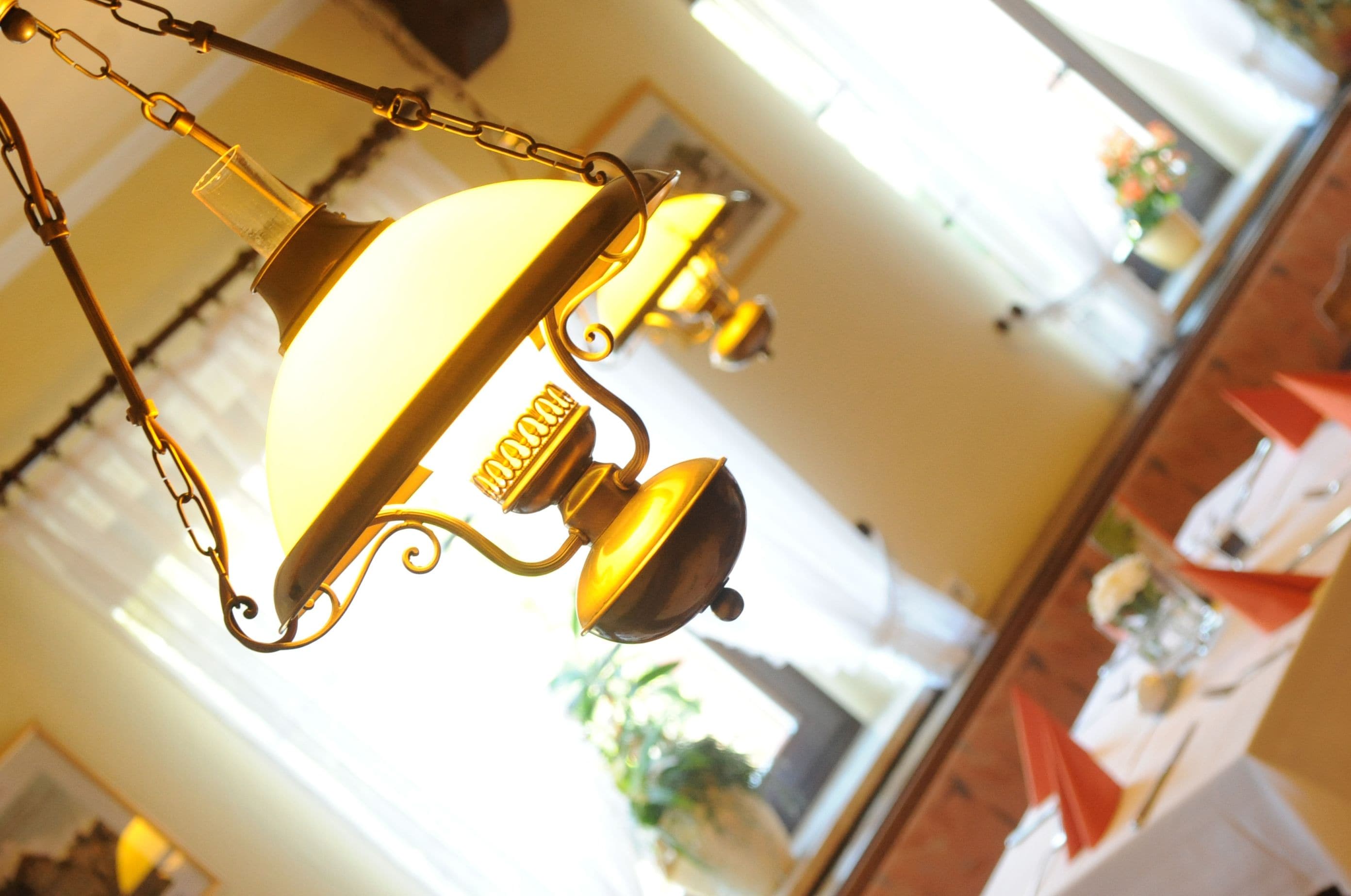 Eine hängende Messinglampe mit einer klaren Glasabdeckung und einem glockenförmigen Fuß.