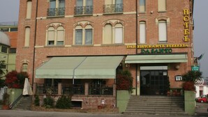 Un hotel con bar y pizzería en la planta baja, que presenta una fachada de ladrillo tradicional y un toldo verde.