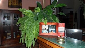 Una mesa de recepción con una planta en maceta, una foto enmarcada y una campana de metal.