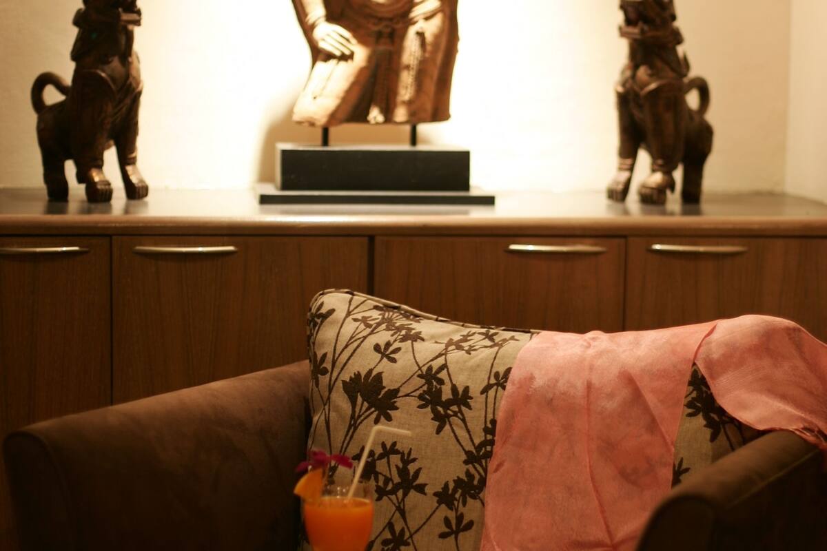 Una sala de estar con un sofá, una estatua y una figura decorativa de caballo sobre un mueble de madera.
