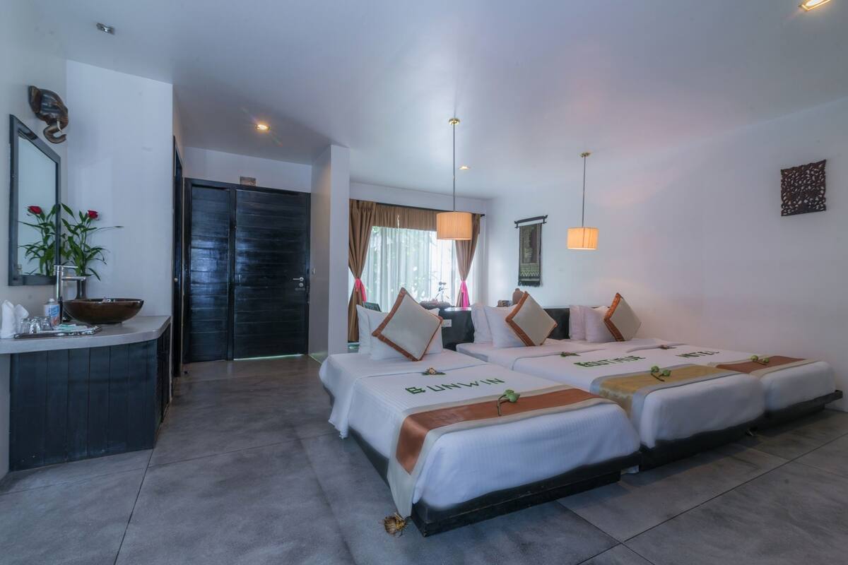 A hotel room with two beds, a desk, and a bathroom.