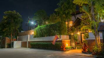 A well-lit residential area with a modern house, a flag, and a statue.