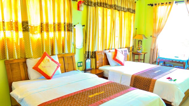 A hotel room with two beds, each with a red and white pillow, and a wooden headboard. - Nhu Phu Hotel (Hue)