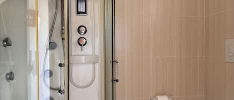 A bathroom with a glass-enclosed shower, a toilet, and a sink.