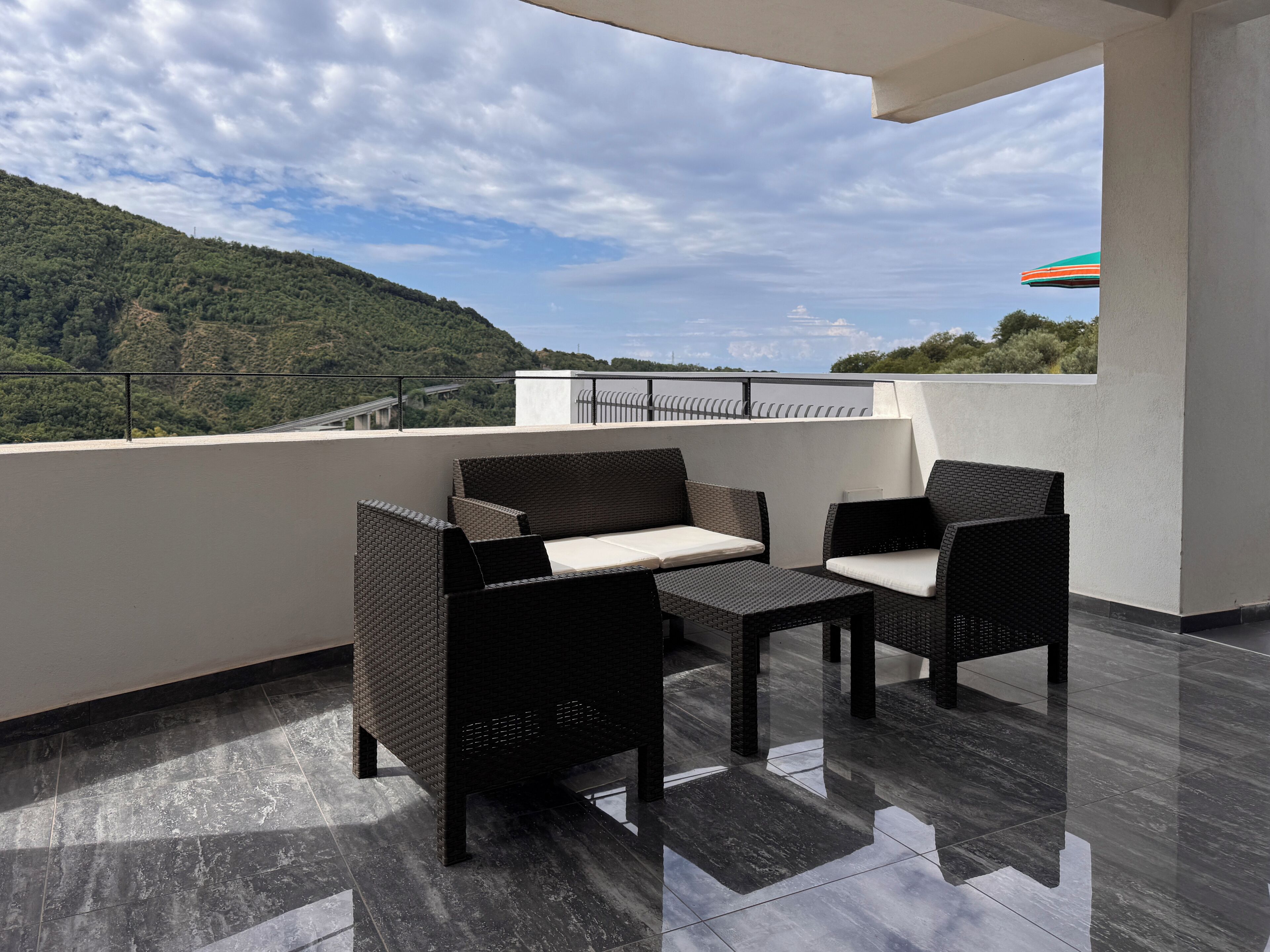 Un balcón con mobiliario de mimbre y vistas a un paisaje montañoso.