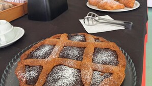 Una mesa de buffet con un pastel de chocolate, croissants y otras pastas.