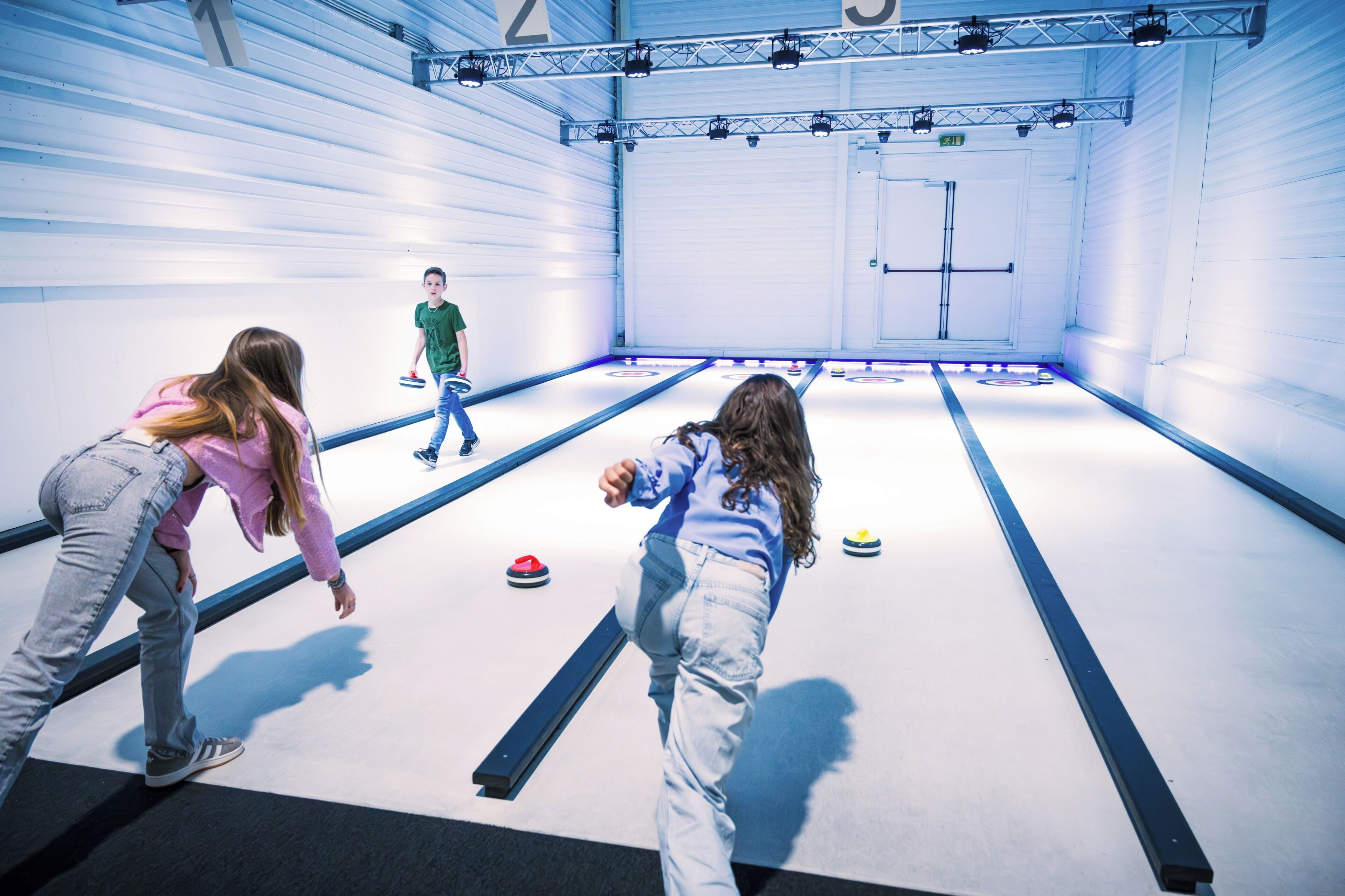 Uma pista de curling coberta com jogadores e pedras de curling.