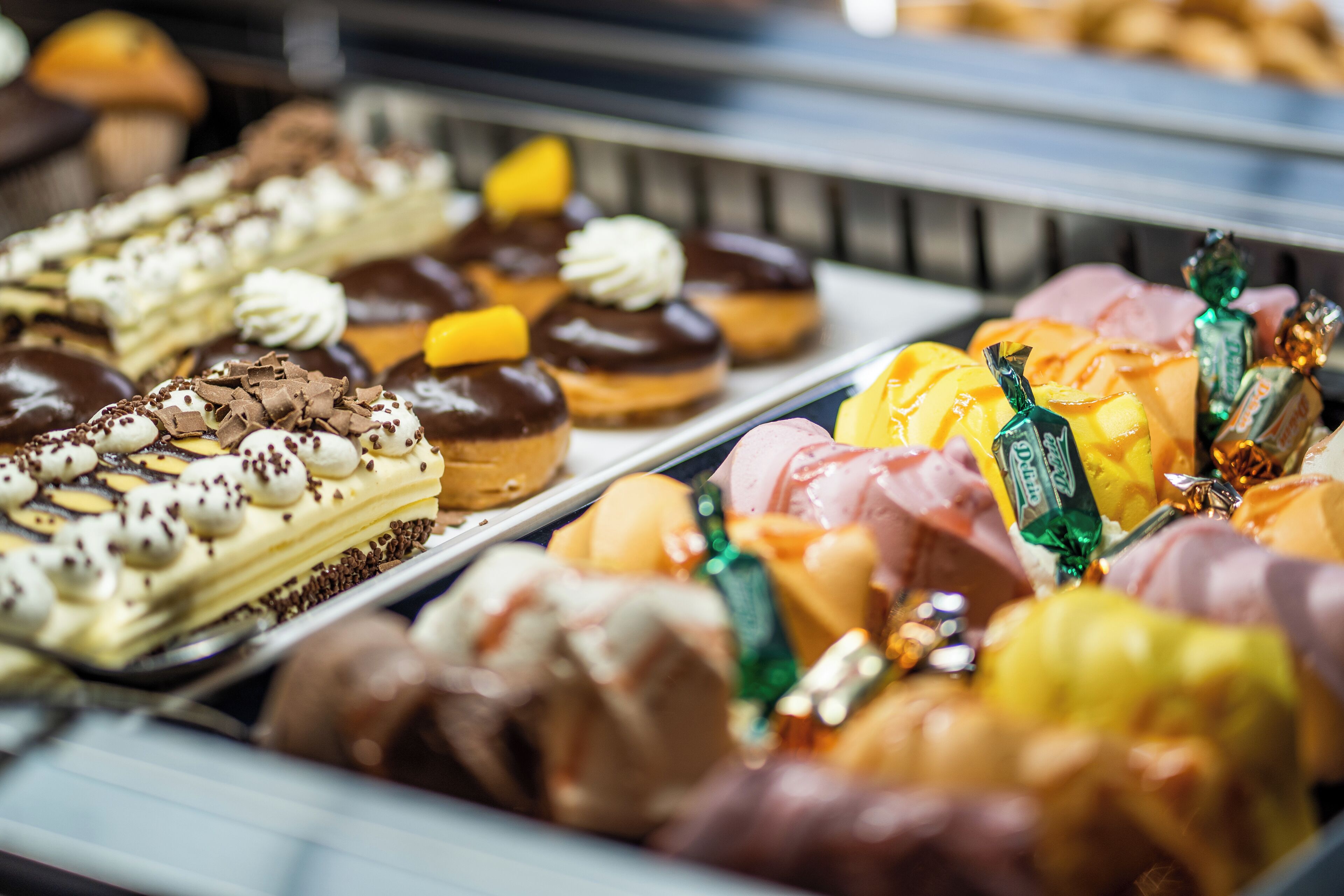 Una variedad de pasteles y postres expuestos en una panadería o pastelería.